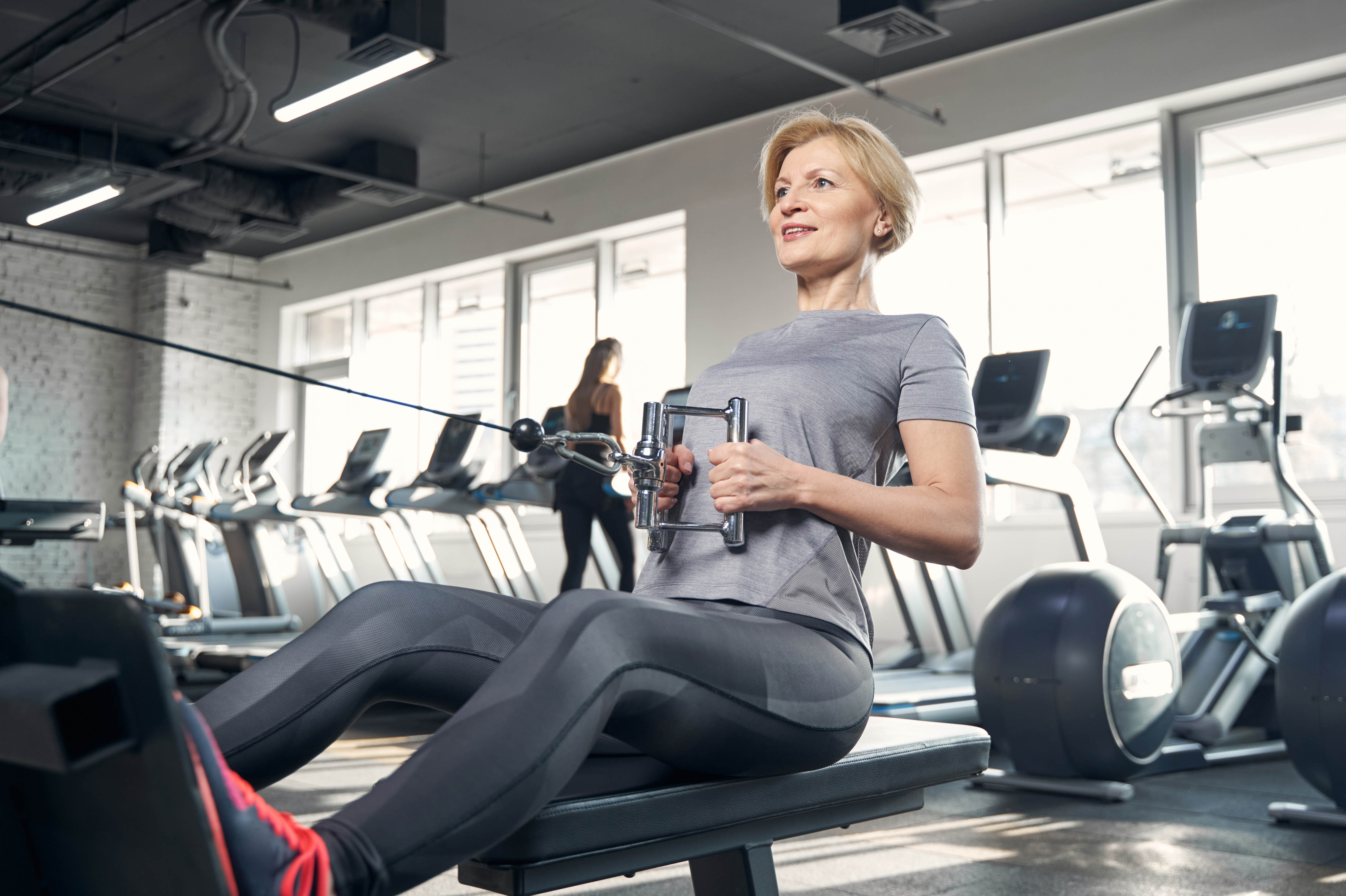 Older woman doing a seated row in the gym on a machine workout